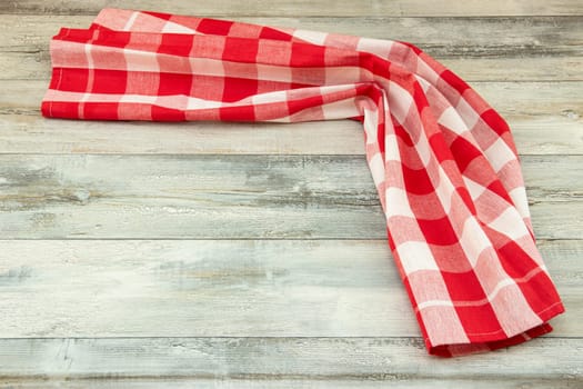 Red checkered tablecloth beautiful folded on rustic bright wooden table. Food recipe template. Template for menu card and chalkboard. Space for designer.