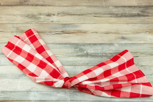 Red white checkered tablecloth beautiful folded on rustic bright wooden table. Food recipe template. Template for menu card and chalkboard. Space for designer.