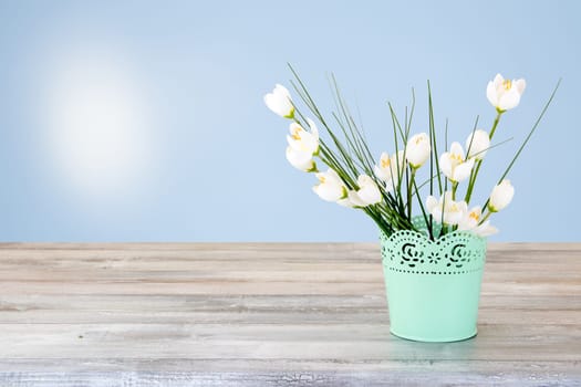 Decorative composition of white flowers Bouquet on rustic bright wooden table. Concept card. The natural bright background with sun is shining. The bunch of white flowers is in decorative green vase.  Empty space for your design. Card concept for mothers day, birthday, aniversary and other events.