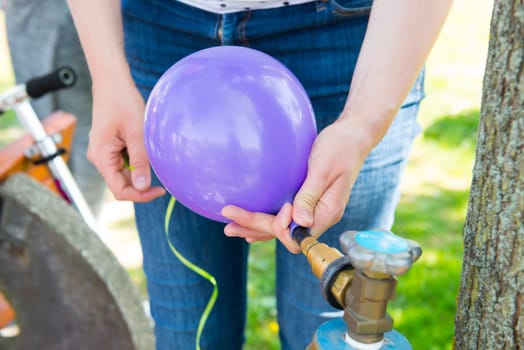 woman filling violet balloon with helium gas