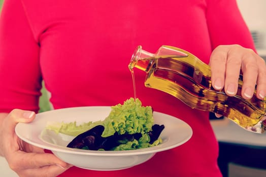 woman with salad on plate and olive oil