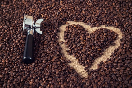 heart in a lot of coffee beans with heart with portafilter