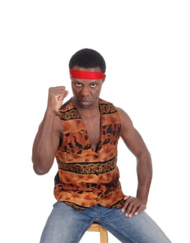 A handsome African American man sitting in a vest making a fist and .looking angry, isolated for white background.