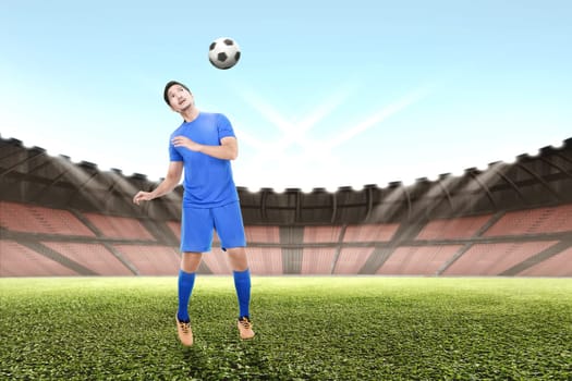 Young asian soccer player man jump and heading the ball on the field