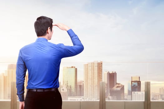 Rear view of asian businessman looking at modern city on day