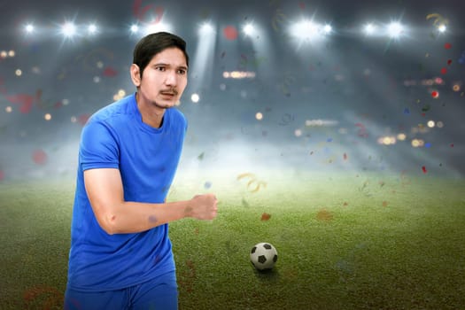 Attractive asian soccer player man running with ball on the field