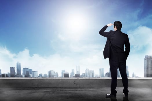 Successful businessman looking out the city from the rooftop