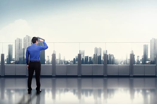Young asian businessman looking at the cityscape from office terrace