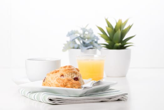 Fresh cranberry lemon scone served with coffee and juice.