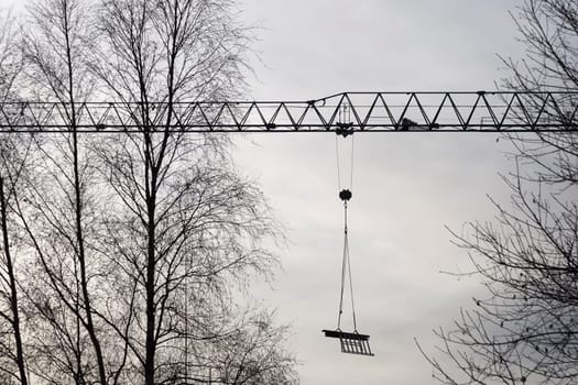Construction Crane with Trees and a cloudy sky.