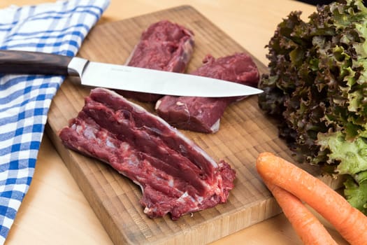 saddle of venison on wooden board with big knife
