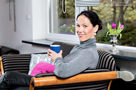 young dark haired woman at home with cup of coffeee relaxing