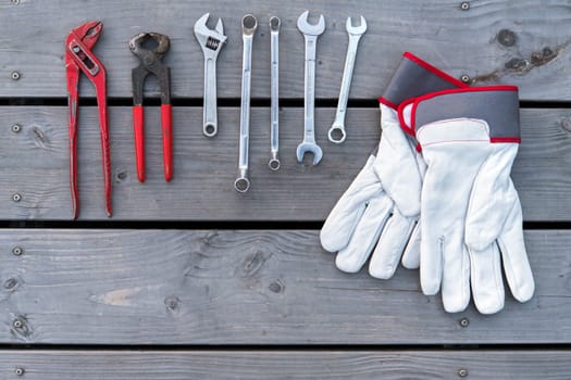 different tools and work gloves on wooden ground