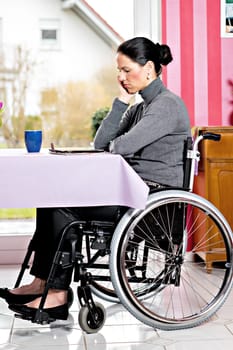 young disabled woman in wheelchair at home with tablet PC