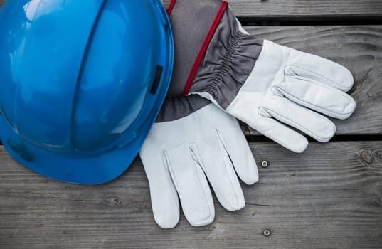blue helmet and work gloves on wooden ground
