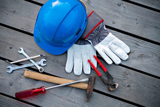 blue helmet different tools and work gloves on wooden ground