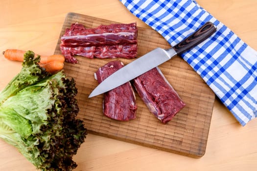 saddle of venison on wooden board with big knife