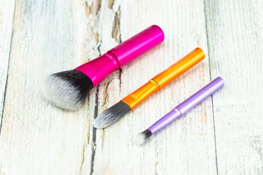 Set makeup brushes on rustic wooden table.