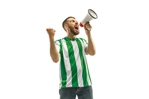Irish fan celebrating on white background. The young man in soccer football uniform as winner with megaphone isolated at white studio. Fan, support concept. Human emotions concept.