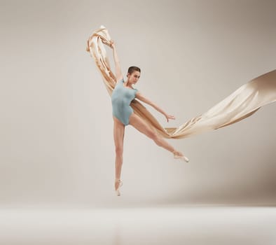 Modern ballet dancer exercising in full body on white studio background. Ballerina or female dancer with silk fabric dancing on white studio background. Caucasian model on pointe shoes