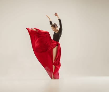 Modern ballet dancer exercising in full body on white studio background. Ballerina or female dancer with silk fabric dancing on white studio background. Caucasian model on pointe shoes