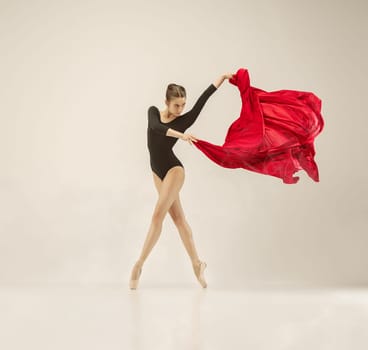 Modern ballet dancer exercising in full body on white studio background. Ballerina or female dancer with silk fabric dancing on white studio background. Caucasian model on pointe shoes