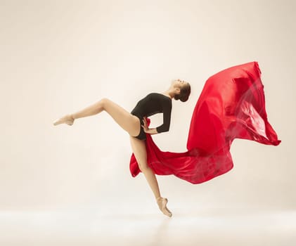 Modern ballet dancer exercising in full body on white studio background. Ballerina or female dancer with silk fabric dancing on white studio background. Caucasian model on pointe shoes