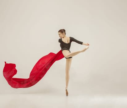 Modern ballet dancer exercising in full body on white studio background. Ballerina or female dancer with silk fabric dancing on white studio background. Caucasian model on pointe shoes
