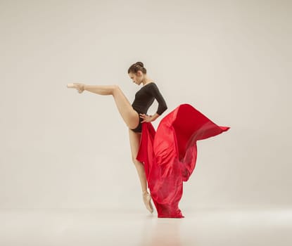 Modern ballet dancer exercising in full body on white studio background. Ballerina or female dancer with silk fabric dancing on white studio background. Caucasian model on pointe shoes