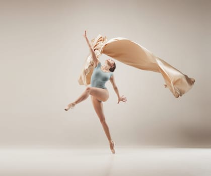 Modern ballet dancer exercising in full body on white studio background. Ballerina or female dancer with silk fabric dancing on white studio background. Caucasian model on pointe shoes