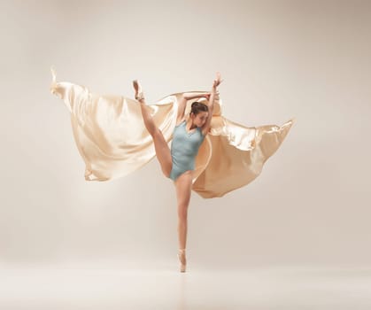 Modern ballet dancer exercising in full body on white studio background. Ballerina or female dancer with silk fabric dancing on white studio background. Caucasian model on pointe shoes