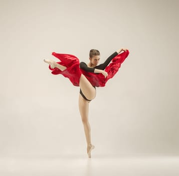 Modern ballet dancer exercising in full body on white studio background. Ballerina or female dancer with silk fabric dancing on white studio background. Caucasian model on pointe shoes