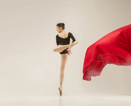 Modern ballet dancer exercising in full body on white studio background. Ballerina or female dancer with silk fabric dancing on white studio background. Caucasian model on pointe shoes