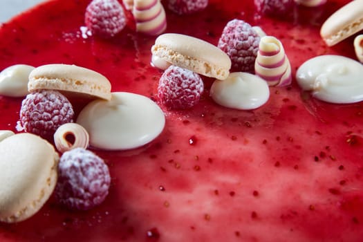 Decoration with raspberries, chocolates and biscuits on a cake