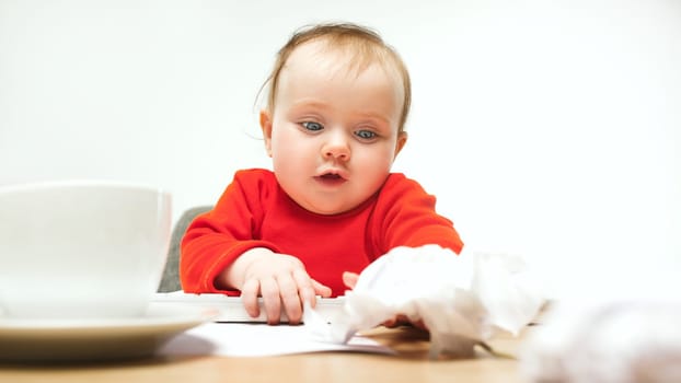 Happy child baby girl sitting with keyboard of modern computer or laptop isolated on a white studio background. early development of modern kids concept. Female caucasian up to a year old baby