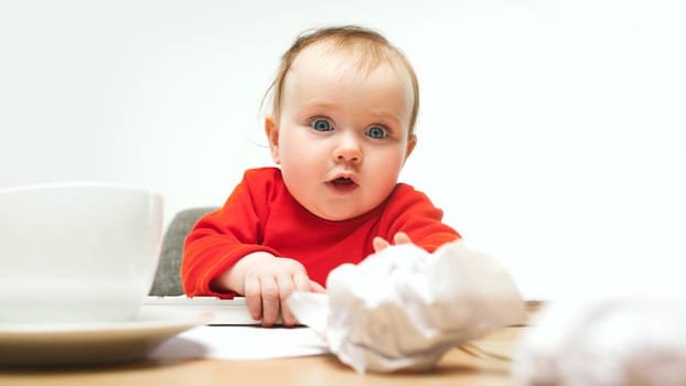 Happy child baby girl sitting with keyboard of modern computer or laptop isolated on a white studio background. early development of modern kids concept. Female caucasian up to a year old baby