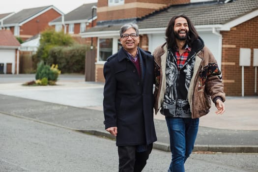 Mid adult man and hiss mature father are laughing as they walk down the street together.
