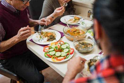 Close up shot of homemade indian food on a family dining table. They are eating curry with salad.