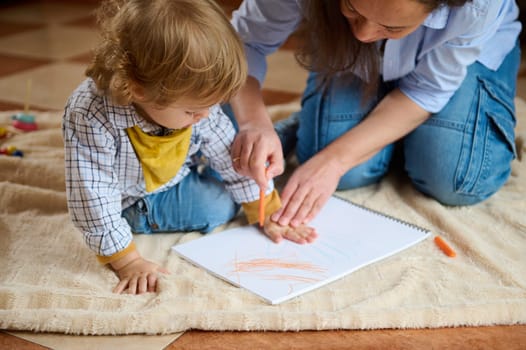 A mother assists her child in coloring in a sketchbook, fostering creativity and bonding during leisure time.