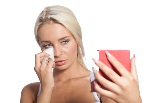 Young woman clean face and eyes with wet wipes, holding mirror, remove make-up, body breast lingerie