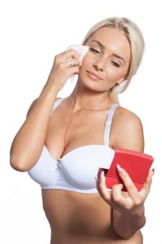 Young woman clean face and eyes with wet wipes, holding mirror, remove make-up, body breast lingerie
