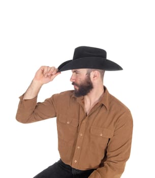 A young man sitting on a chair in profile wearing a black.cowboy hat and looking away, isolated for white background.