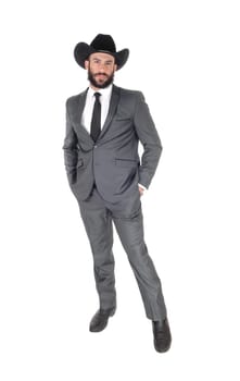 A handsome man standing in a gray suit and cowboy hat with his hands.in his pocket, with beard and mustache, isolated for white background.