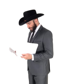 A business man standing in profile in a gray suit and cowboy hat reading.his papers, isolated for white background.