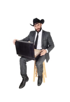 A handsome young business man sitting with his briefcase on his knees.wearing a black cowboy hat, isolated for white background.