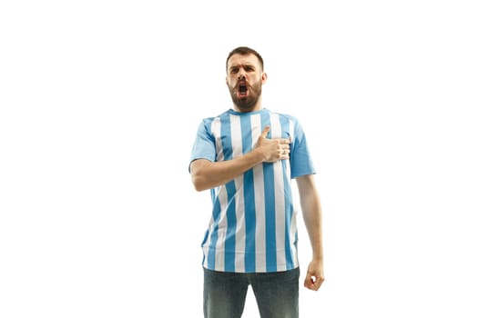 The young Argentinean fan celebrating on white background. The young man in soccer football uniform singing a hymn isolated at white studio. Fan, support concept. Human emotions concept.