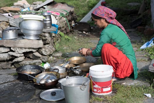 Woman cleaning utensils outdoors in Shimla, Himachal Pradesh, India.