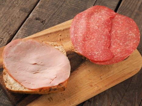 Tasty organic buns with salami and kasseler ham on a rustic wooden table