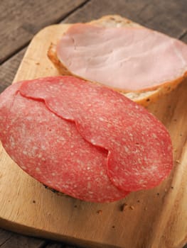 Tasty organic buns with salami and kasseler ham on a rustic wooden table