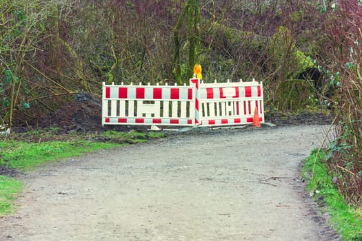Red whitepolice line with yellow lettering for crime scene investigation in a rural area in the forest.